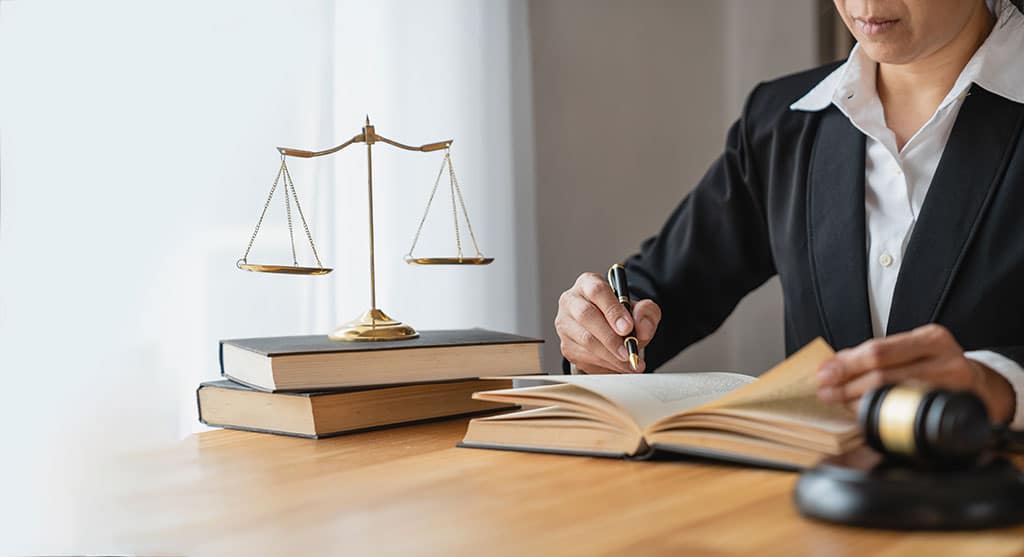 A woman working on legal research with tools and documents.